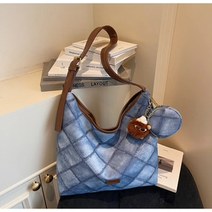 Detail view of denim texture bucket bag with leather strap and plush animal charm