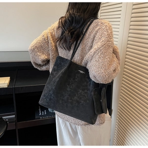 Detail of vintage black tote bag with matching pouch on model in home office setting