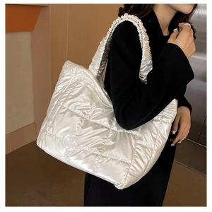 Silver quilted tote bag with ruffled handle detail shown on model in a modern room