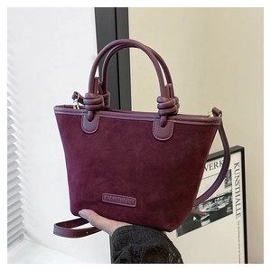 Dettaglio della texture scamosciata bordeaux e del manico annodato della borsa a secchiello