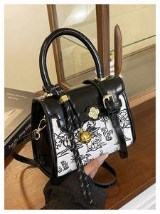Detail of color-block crossbody bag featuring ink wash print and gold bell pendant charm