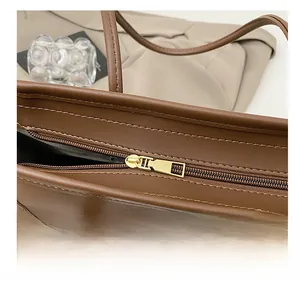 Detail view of the smooth golden metal zipper on a premium brown leather tote bag