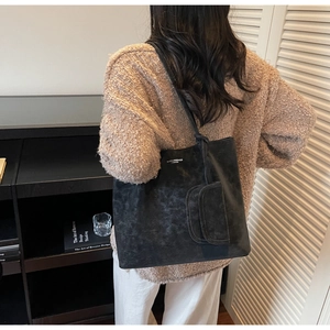 Detail of black matte suede tote bag with small pouch showing fit on model's shoulder