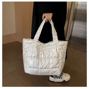 Close-up of white glossy quilted tote bag with pleated handles and shiny finish