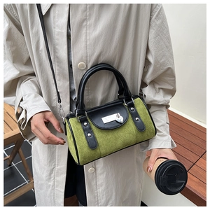 Détails du sac cylindrique en daim vert avec poignées noires et pendentif en cœur