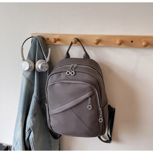 Detail of dark brown backpack with pebble leather texture and metal chain accent