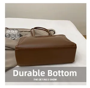 Detailed view of the wear-resistant bottom and stitching on this brown leather tote bag