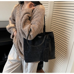 Close-up of large black suede tote bag with shoulder strap and a small side pouch