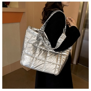 Detail of silver quilted tote bag featuring metallic finish and ruffled shoulder strap