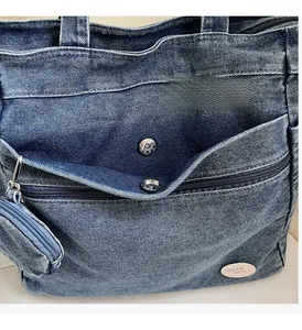 Detail of blue denim tote bag with silver button pocket and 'good luck!' patch label