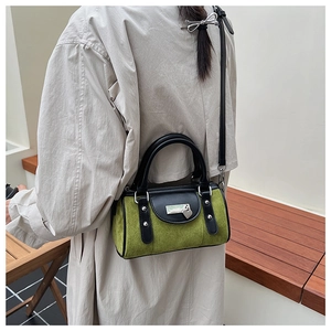 Détail du sac cylindre Boston en daim vert avec lanières noires et pendentif en cœur