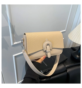 Detail of beige shoulder bag with fabric texture flap and U-shaped leather buckle clasp