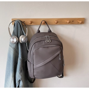 Detail of dark grey lychee leather backpack with silver zippers and stylish ring pullers