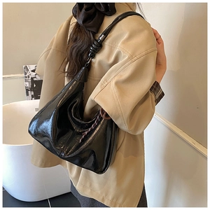 Detail view of the glossy black hobo bag showing large capacity and knotted strap design
