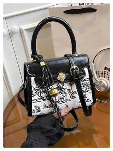 Close-up of ink landscape print bag with golden flower lock and bell tassel detail