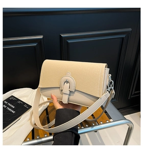 Detailed close-up of a beige crossbody bag featuring textured patchwork and a buckle strap