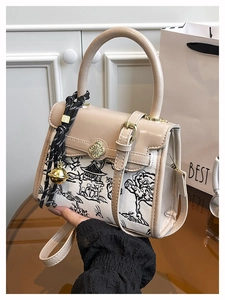 Detail of canvas bag with traditional ink print, golden floral clasp and bell charm