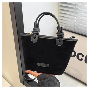 Dettaglio della borsa tote in pelle scamosciata nera con manico a nodo e logo