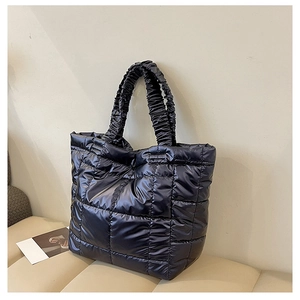 Close-up of black quilted tote bag with glossy nylon texture and ruched shoulder strap