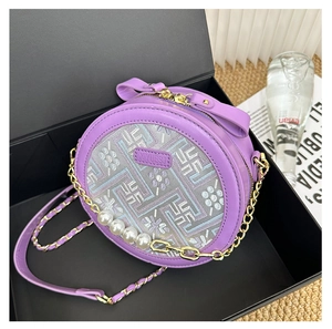 Close-up of purple round cross-body bag featuring floral embroidery and pearl chain detail