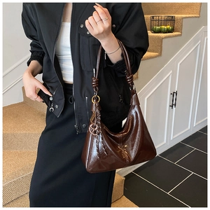 Detail of vintage brown glossy hobo bag with knotted shoulder strap and fringe charm