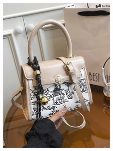 Close-up of contrast crossbody bag with landscape print fabric and golden floral clasp