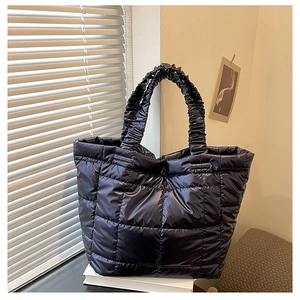 Detail of black quilted puffer tote bag with elegant scrunchie handles and square stitching