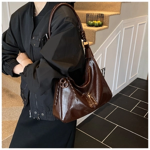 Detail of dark mahogany oil-wax leather shoulder bag with decorative knot and white stitching