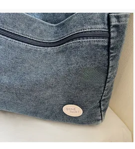 Macro view of blue denim tote bag texture with good luck embroidery and zipper detail