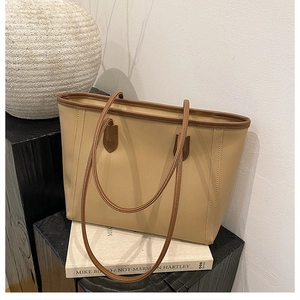 Detailed view of beige tote bag with brown handles on artistic book backdrop