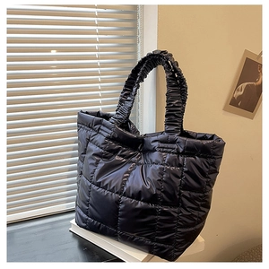 Detailed view of black quilted puffer tote bag featuring unique ruched handle design