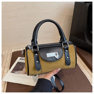 Détail du sac seau en daim moutarde avec clous argentés et pendentif cœur en main