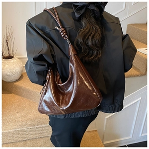 Detail view of the knot decoration on a dark brown glossy hobo shoulder bag