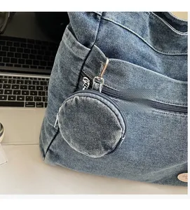 Detail of blue denim tote bag featuring a detachable round coin purse and metal hardware