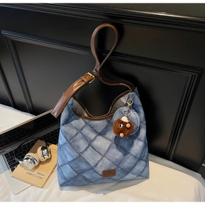 Blue quilted bucket bag with leather strap and plush charm detail in casual setting