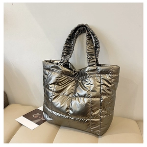 Detail of metallic quilted tote bag with champagne gold finish on a beige leather bench