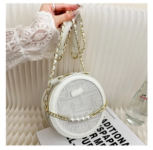 Close-up of a white round crossbody bag featuring floral embroidery and large pearls