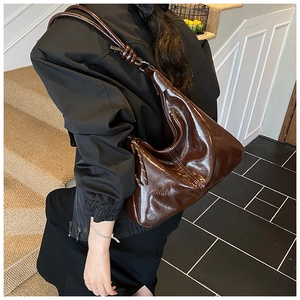 Detail of the oversized brown oil-wax leather hobo bag with knotted strap and glossy finish