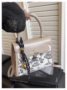 Detail of color-block bag with mountain landscape print and golden floral clasp