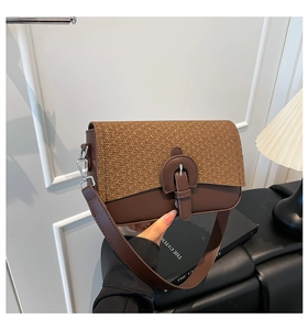 Detail of minimalist brown crossbody bag featuring woven texture and horseshoe buckle accent