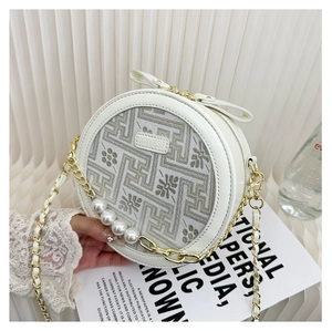 Close-up of white round crossbody bag with geometric embroidery and pearl chain detail