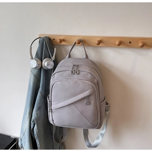 Close-up of lilac pebbled leather backpack with metallic ring zipper and diagonal front pocket