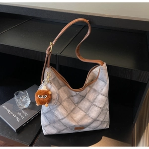 Detail of retro quilted hobo bag with brown strap and plush monster charm on rack