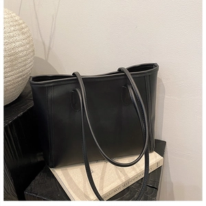 Close-up of black leather tote bag details with reinforced stitching and slim shoulder straps