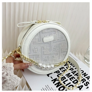 Detail of white round pearl crossbody bag with floral embroidery and gold chain strap