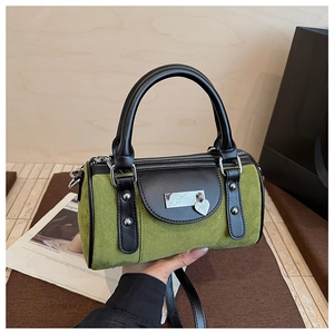 Détail du sac Boston en daim vert avec breloque cœur et poignée en cuir noir