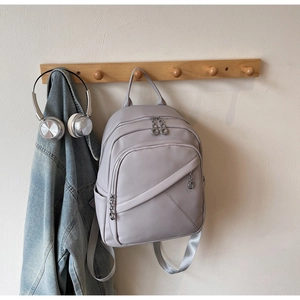 Detail of lavender faux leather backpack showing silver ring zippers and fabric straps
