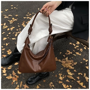 Detail of vintage brown tote bag with large knot handle on an outdoor wooden bench
