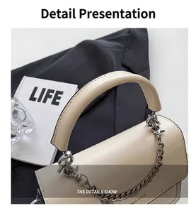 Detail einer cremefarbenen Lederhandtasche mit dickem Griff und silberner Zierkette