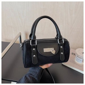 Détail du sac boston en cuir noir avec ferrures argentées et pendentif en cœur
